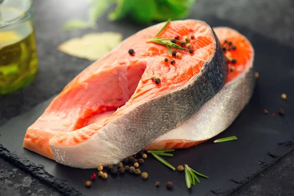 Łososia. Surowy stek z pstrąga z ziołami na czarnym łupku oświetlenie tła — Zdjęcie stockowe