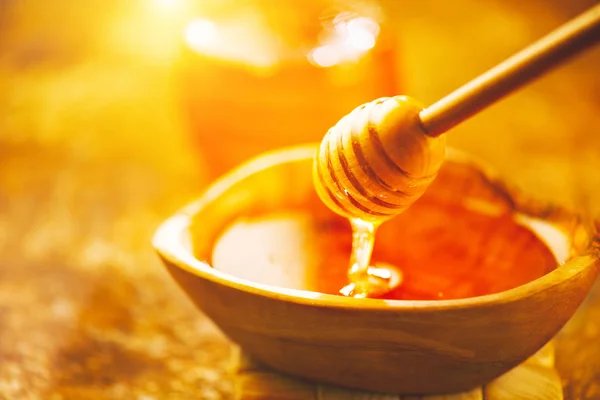 Honey dripping from honey dipper in wooden bowl. Healthy organic — Stock Photo, Image