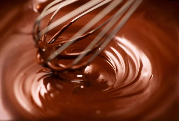 Шоколад. Смешивание расплавленного тёмного шоколада с венчиком. Крупный план — стоковое фото