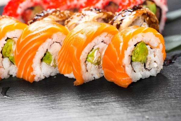 寿司卷特写 餐厅的日式食品 在黑色石板背景上与鲑鱼 蔬菜和飞鱼鱼子酱一起滚动 — 图库照片