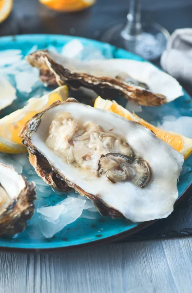 Ostras frescas primer plano en plato azul, mesa servida con ostras , — Foto de Stock