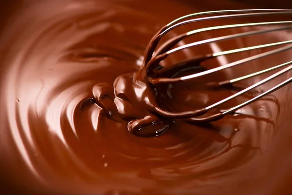 Chocolade. Mengen van gesmolten donkere chocolade met een garde. Close-up van — Stockfoto