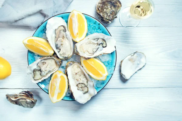 Ostras frescas de cerca en plato azul, mesa servida con ostras , — Foto de Stock