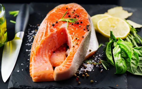Zalm. Rauwe forel vis Steak met kruiden en citroen op zwarte leisteen — Stockfoto