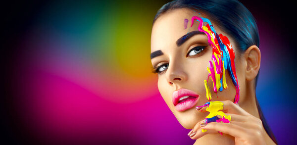 Female model with colorful paints on face. Portrait of woman with flowing liquid paint.