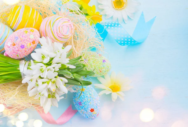 Easter eggs in the nest with spring flowers over wooden backgrou — Stock Photo, Image