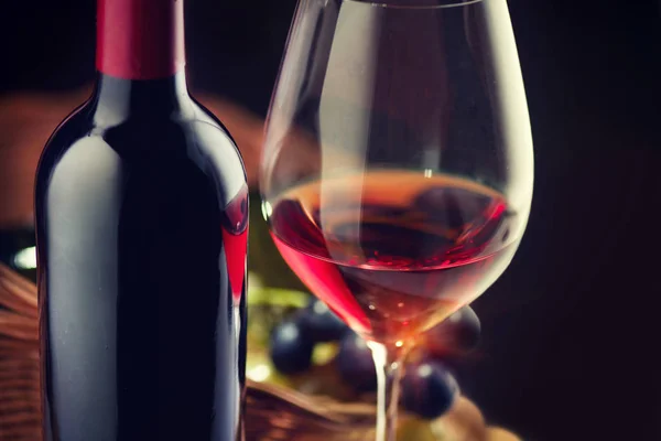 瓶和一杯红酒与成熟的葡萄在黑色背景 — 图库照片