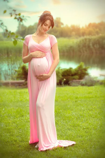 Gravid lycklig kvinna smekande hennes mage i sommarpark. Full Le — Stockfoto