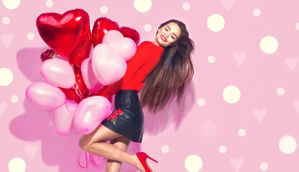 バレンタインデーだピンクの背景の上に楽しみを持っているカラフルな気球を持つ美少女 ストック写真