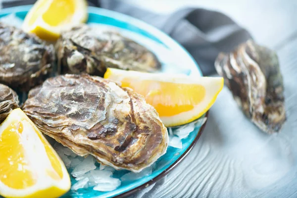 新鮮な牡蠣をブループレートにクローズアップし、カキを添えたテーブルを提供, ロイヤリティフリーのストック画像