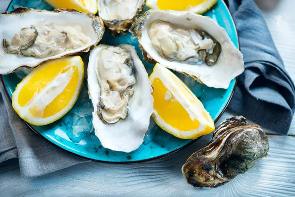 Fresh oysters close-up on blue plate, served table with oysters, Royalty Free Stock Photos