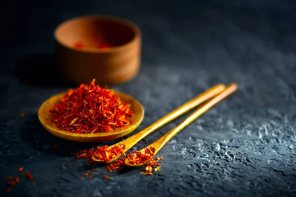 Saffron spices. Saffron on black stone table in a wood bowl and Stock Image