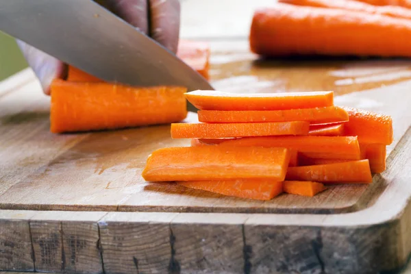 Hombre cortando zanahoria en la mesa — Foto de Stock