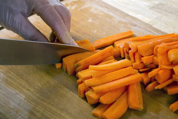 Hombre cortando zanahoria en la mesa — Foto de Stock