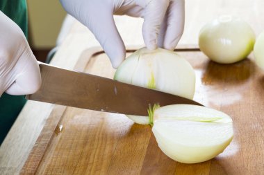 Adam beyaz soğanı bıçakla kesiyor..