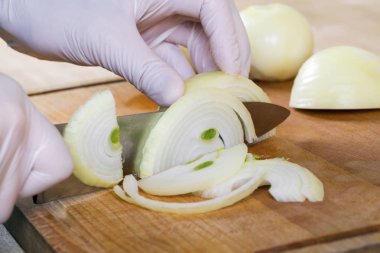 Adam beyaz soğanı bıçakla kesiyor..