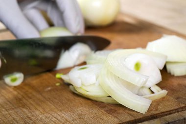Adam beyaz soğanı bıçakla kesiyor..