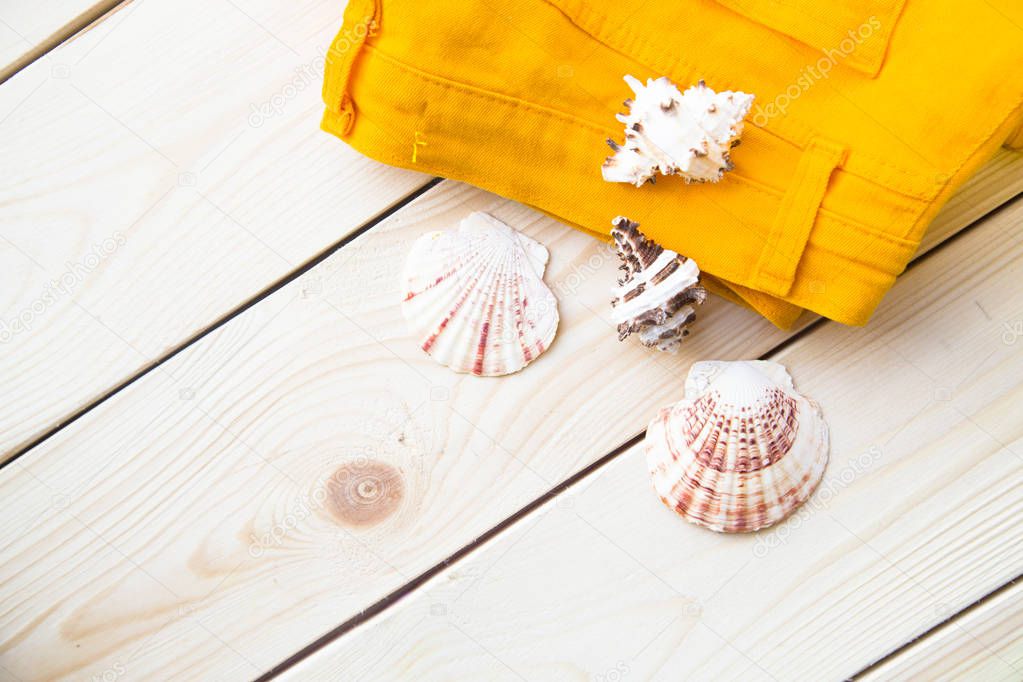 Preparing for vacation, travel or journey. Travel planning. Yellow jeans on white wooden background. Instagram top view