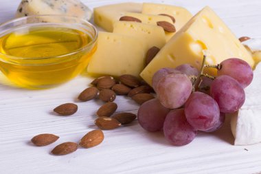 Cheese cuts with figs, nuts, honey, grapes on a wooden boards background. Top view