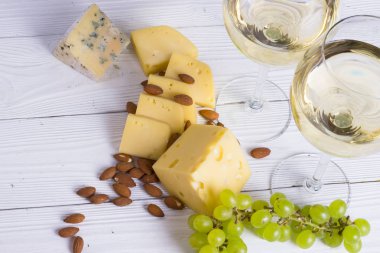 Aperatifler - çeşitli peynir, incir, fındık, bal, üzüm ahşap Komiteler arka plan üzerinde beyaz şarapla kadeh. Üstten görünüm