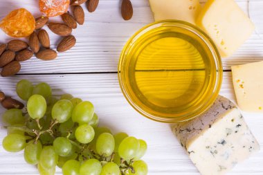 Cheese cuts with figs, nuts, honey, grapes on a wooden boards background. Top view