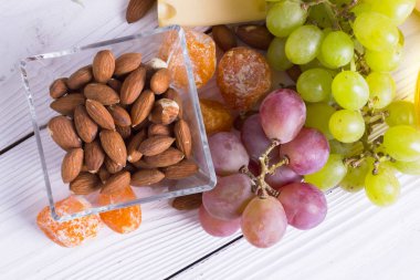 Cheese cuts with figs, nuts, honey, grapes on a wooden boards background. Top view
