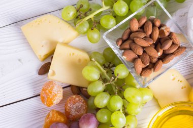 Cheese cuts with figs, nuts, honey, grapes on a wooden boards background. Top view