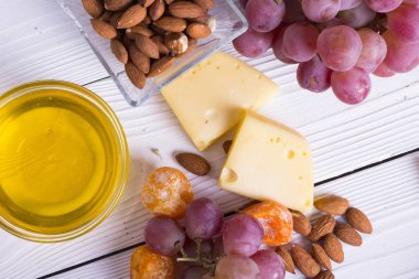 Cheese cuts with figs, nuts, honey, grapes on a wooden boards background. Top view