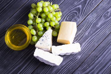 Peynir incir, fındık, bal, üzüm ile bir karanlık rustik ahşap Komiteler arka plan üzerinde keser. Üstten görünüm