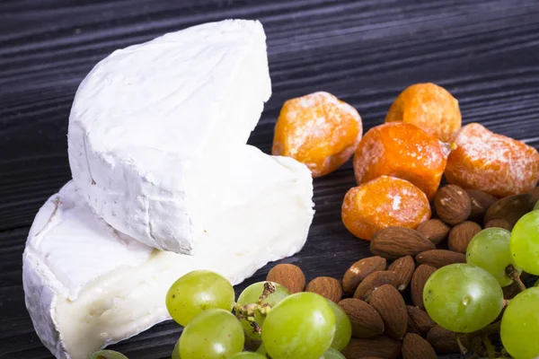 Peynir incir, fındık, bal, üzüm ile bir karanlık rustik ahşap Komiteler arka plan üzerinde keser. Üstten görünüm