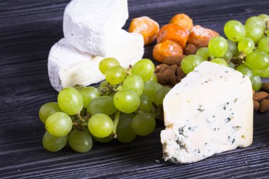 Peynir incir, fındık, bal, üzüm ile bir karanlık rustik ahşap Komiteler arka plan üzerinde keser. Üstten görünüm