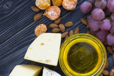 Peynir incir, fındık, bal, üzüm ile bir karanlık rustik ahşap Komiteler arka plan üzerinde keser. Üstten görünüm