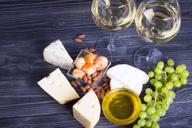 Bir bardak beyaz şarap ile peynir keser, incir, fındık, bal, üzüm karanlık rustik ahşap Komiteler arka plan üzerinde. Üstten görünüm