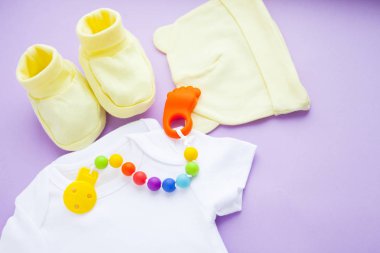 Sarı Bebek Patikleri. Çocuk ayakkabı ve oyuncaklar mor zemin üzerine. Yeni doğan. Üstten görünüm