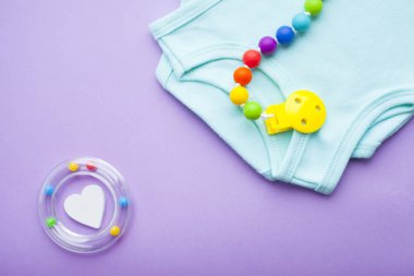 Sarı Bebek Patikleri. Çocuk ayakkabı ve oyuncaklar mor zemin üzerine. Yeni doğan. Üstten görünüm