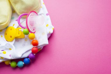 Sarı Bebek Patikleri. Çocuk ayakkabı ve pembe bir arka plan üzerinde oyuncaklar. Yeni doğan. Üstten görünüm