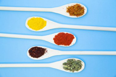 Pişirme sıcak baharatlı yemek kavramı. Kuru baharat, fasulye ve tahta kaşıklar, açık mavi renkli, otlar görünümü top