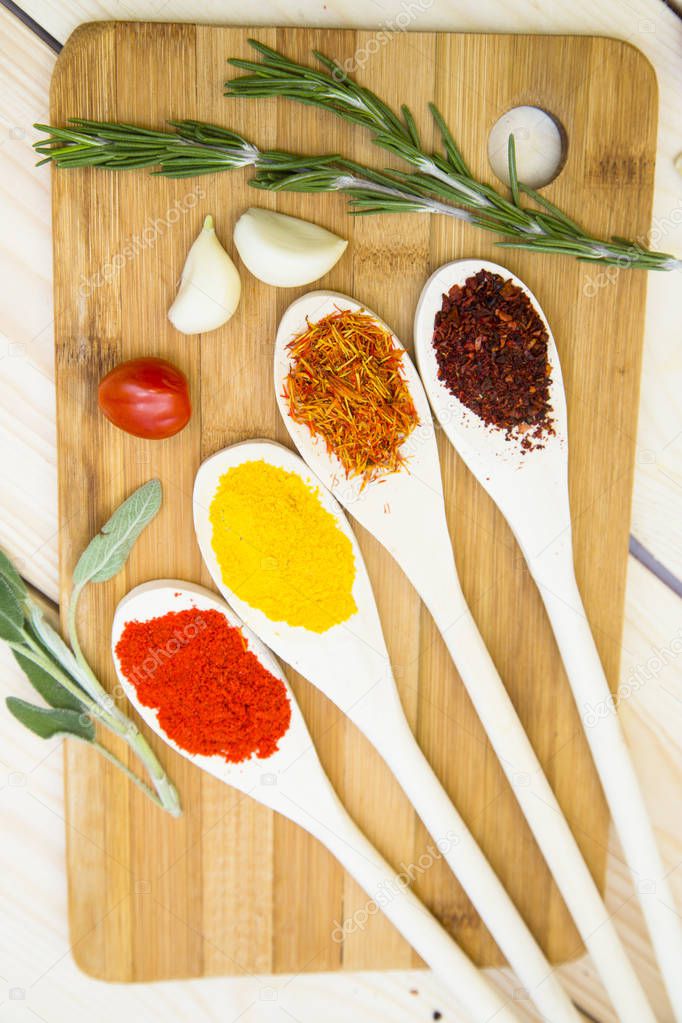 Cooking Hot Spicy Food Concept. Dry spices and herbs in wooden spoons on a cutting board, close up, top view