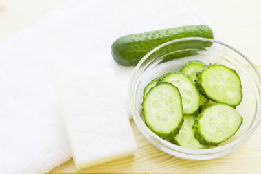 Salatalık ev spa ve saç bakım kavramı. Salatalık, petrol, sabun, maske, banyo havlu kavanoz şişe dilimlenmiş. Beyaz tahta arka plan. Portre