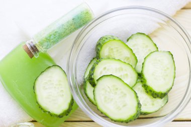 Salatalık ev spa ve saç bakım kavramı. Salatalık, petrol, sabun, maske, banyo havlu kavanoz şişe dilimlenmiş. Beyaz tahta arka plan. Portre