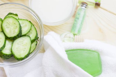 Salatalık ev spa ve saç bakım kavramı. Salatalık, petrol, sabun, maske, banyo havlu kavanoz şişe dilimlenmiş. Beyaz tahta arka plan. Portre