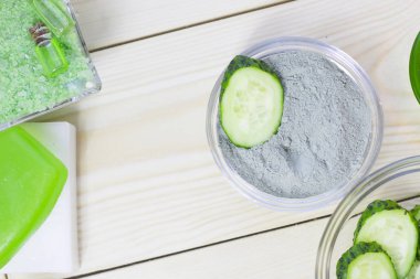 Salatalık ev spa ve saç bakım kavramı. Dilimlenmiş salatalık, yağ, deniz tuzu, banyo havlu şişe. Beyaz tahta arka plan. Portre