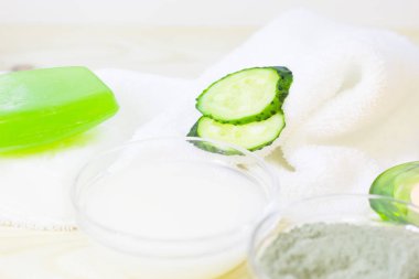 Salatalık ev spa ve saç bakım kavramı. Dilimlenmiş salatalık, yağ, deniz tuzu, banyo havlu şişe. Beyaz tahta arka plan. Portre