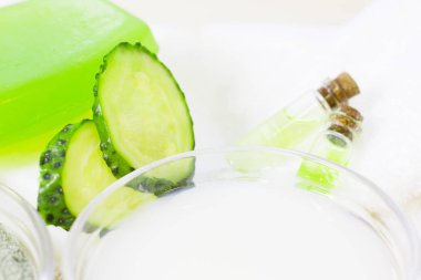 Salatalık ev spa ve saç bakım kavramı. Dilimlenmiş salatalık, yağ, deniz tuzu, banyo havlu şişe. Beyaz tahta arka plan. Portre