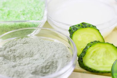 Salatalık ev spa ve saç bakım kavramı. Dilimlenmiş salatalık, yağ, deniz tuzu, banyo havlu şişe. Beyaz tahta arka plan. Portre