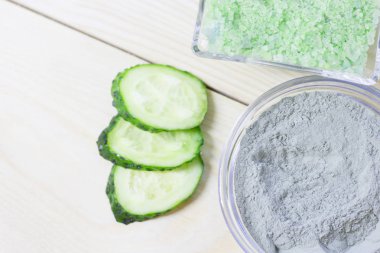 Salatalık ev spa ve saç bakım kavramı. Dilimlenmiş salatalık, yağ, deniz tuzu, banyo havlu şişe. Beyaz tahta arka plan. Portre