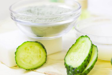 Salatalık ev spa ve saç bakım kavramı. Dilimlenmiş salatalık, yağ, deniz tuzu, banyo havlu şişe. Beyaz tahta arka plan. Portre