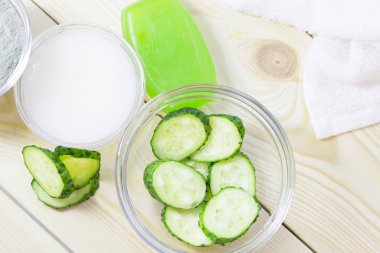 Salatalık ev spa ve saç bakım kavramı. Dilimlenmiş salatalık, petrol, deniz tuzu, mum, banyo havlu şişe. Beyaz tahta arka plan. Portre