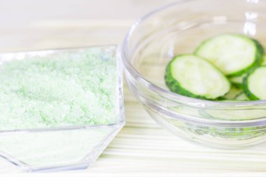 Salatalık ev spa ve saç bakım kavramı. Dilimlenmiş salatalık, yağ, deniz tuzu, banyo havlu şişe. Saman açık renkli. Portre