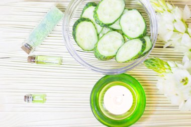 Salatalık ev spa ve saç bakım kavramı. Salatalık, yağ, mum, banyo havlu şişe dilimlenmiş. Saman açık renkli. Portre